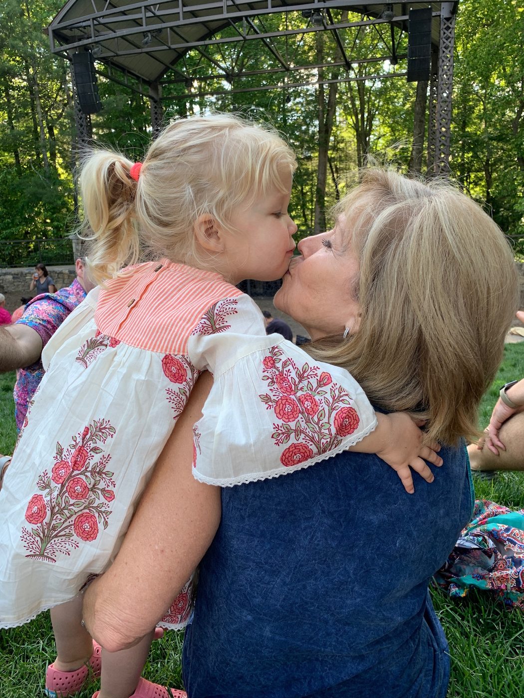A toddler kissing Sue on the lawn at an outdoor concert